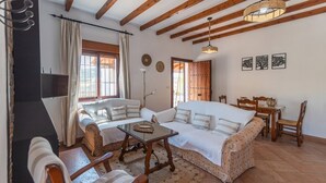 A cozy living room with a sofa, a coffee table, and a dining area with a table and chairs. - Casa La Era Villanueva de la Concepción by Ruralidays (Málaga)