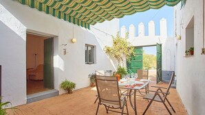 A patio with a table set for dining, potted plants, and a door leading to an interior space. - Cortijo de Liche Arcos de la Frontera by Ruralidays (Cádiz)