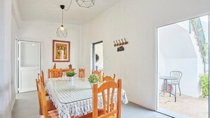 A dining area with a table, chairs, a hanging light fixture, a painting, and a door leading to an outdoor patio. - Cortijo de Liche Arcos de la Frontera by Ruralidays (Cádiz)
