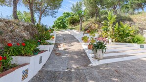 Eine Steintreppe mit weißen Geländern, umgeben von Blumentöpfen und Blumen.