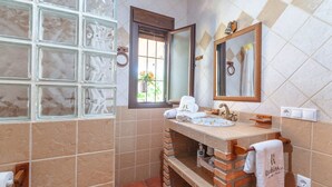A bathroom with a tiled floor, a window with a view, a sink with a mirror, and a towel rack.