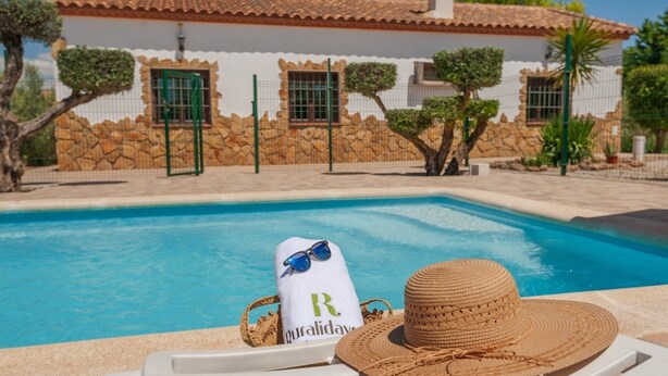 A poolside area with a lounge chair, a towel with a logo, and a straw hat.
