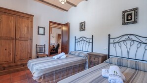 A bedroom with two beds, wooden wardrobe, and a mirror.