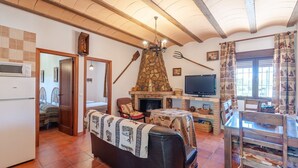 A cozy living room with a stone fireplace, a television, and a dining area with wooden furniture.