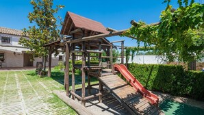 A playground with a wooden climbing structure and a red slide.