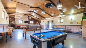 A spacious indoor recreational area with a pool table, foosball table, and ping pong table.