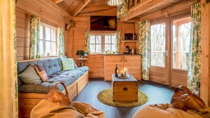 Interior acogedor de una cabaña con un sofá, un cofre de madera y una zona de comedor.