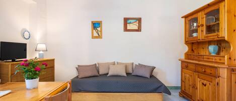 Een slaapkamer met een bed, een houten kast, een televisie en een tafel met een plant.