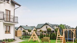 A residential area with houses, a grassy lawn, and wooden play structures. - Awesome apartment in Karwia (Karwia)