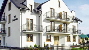 A two-story building with balconies, a visible entrance, and a clear sky. - Awesome apartment in Karwia (Karwia)