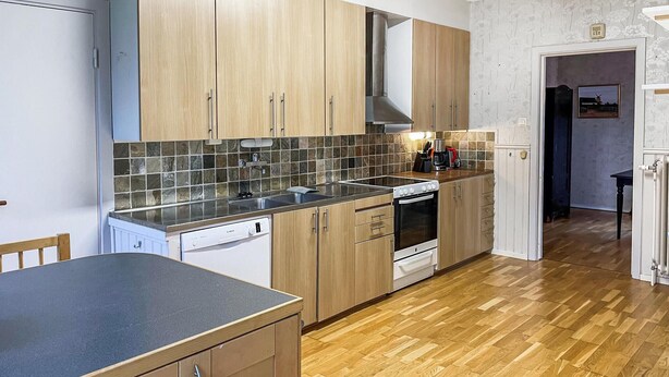 A kitchen with wooden cabinets, a dishwasher, a stove, and a tiled backsplash.