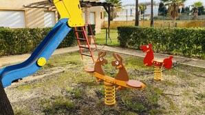 A playground with a blue slide, seesaw, and a red and brown seesaw.