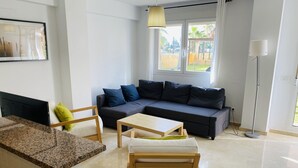 A modern living room with a dark grey sectional sofa, a wooden coffee table, and a small wooden table.