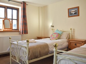 A bedroom with a bed, a nightstand, a dresser, a window with curtains, and a wall-mounted picture. - Combe Cottage-UK42228 (Near Tebay)