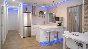 Een moderne keuken met een roestvrijstalen koelkast, witte kasten en een centraal kookeiland met barkrukken.