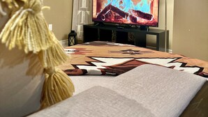 Une chambre avec un lit, un téléviseur diffusant une image de feu de cheminée, une lampe fixée au mur et un crâne décoratif.