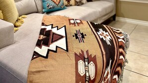 Un salon avec un canapé, des coussins à motifs et une couverture.