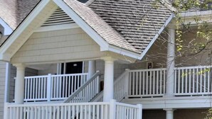 A two-story house with a front porch, a mailbox, and a street sign.