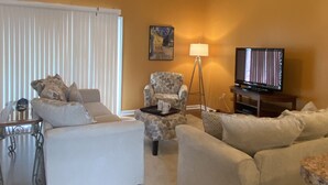 A living room with a ceiling fan, a television, and two couches.
