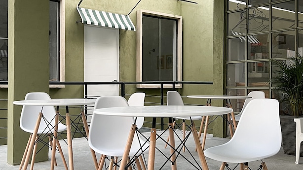 Uma sala de reuniões moderna com mesas e cadeiras brancas, paredes verdes e grandes janelas.