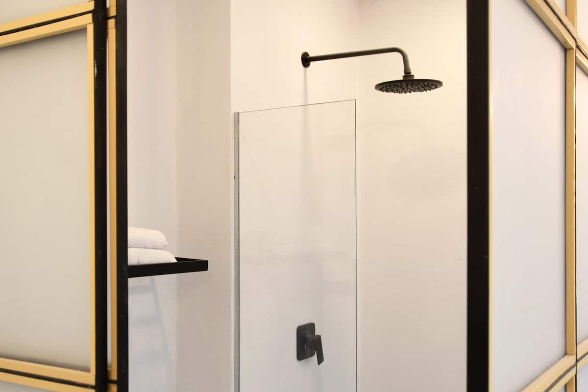A modern bathroom with a glass shower enclosure, a white toilet, and a black towel rack.