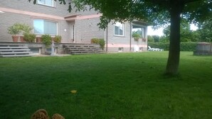 Un immeuble résidentiel avec une façade en pierre, une cour verdoyante et des plantes en pot.