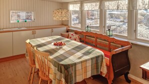 Een gezellig eetgedeelte met een geruit tafelkleed, houten stoelen en een bank.