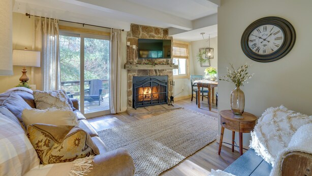 A cozy living room with a fireplace, a comfortable sofa, and a dining area. - 1 Mi to Sugar Mountain! Cozy Lodge-Style Condo (Banner Elk)