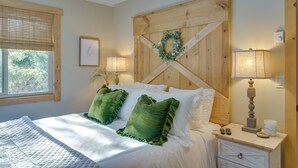 A bedroom with a wooden headboard, a bed with white linens and green pillows, a bedside table with a lamp, and a window with blinds. - 1 Mi to Sugar Mountain! Cozy Lodge-Style Condo (Banner Elk)