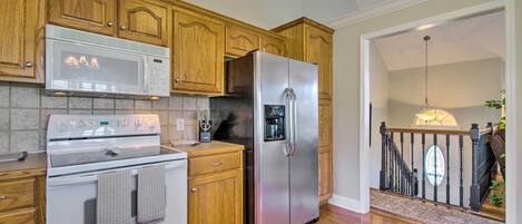 A kitchen with wooden cabinets, a stainless steel refrigerator, a microwave, and an oven.