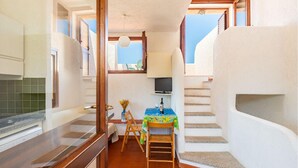 Eine schmale Küche mit Essbereich, einem kleinen Tisch mit Tischdecke und einer Treppe, die zu einem Balkon führt.