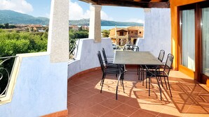 Une terrasse avec une table et des chaises, une vue sur la campagne et un bâtiment en arrière-plan.