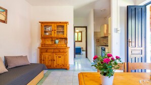 A cozy living room with a sofa, wooden cabinet, and a dining table with a potted plant. - 1 bedroom nice apartment in San Teodoro (San Teodoro)