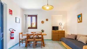 A cozy living room with a sofa, a TV, and a dining area with a table and chairs. - 1 bedroom nice apartment in San Teodoro (San Teodoro)