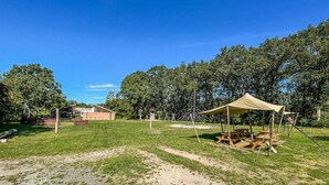 A campsite with a tent, picnic tables, and a barn in the background. - Stunning (sta)caravan in Hoogersmilde (Hoogersmilde)