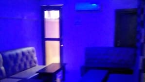 Una habitación tenuemente iluminada con luces azules, un sofá, una mesa y un banco.