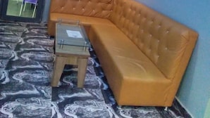 Un rincón con una zona de estar que incluye un sofá de cuero, una pequeña mesa de madera, una mesa auxiliar de cristal y un suelo estampado.