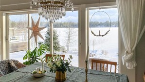 A dining area with a table set for two, a star decoration, and a view of a snowy landscape through large windows. - Lovely home in Taberg with kitchen (Taberg)