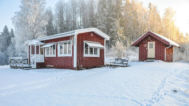 Two wooden cabins with white trim, set in a snowy forest.