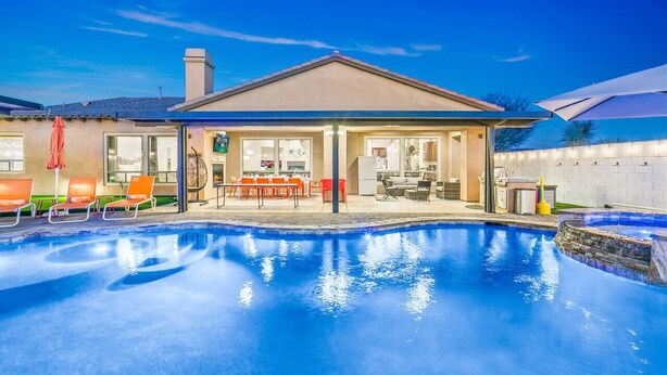 Ein Schwimmbecken mit Liegestühlen und einer überdachten Terrasse.