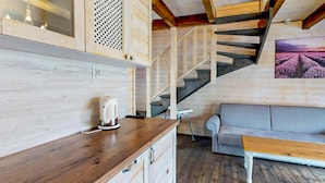 Ein Holzinnenraum mit Küchenzeile, einer Couch und einer Treppe.