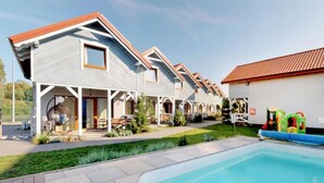 Ein modernes, zweistöckiges Haus mit Pool, überdachter Terrasse und umzäunter Gartenfläche.