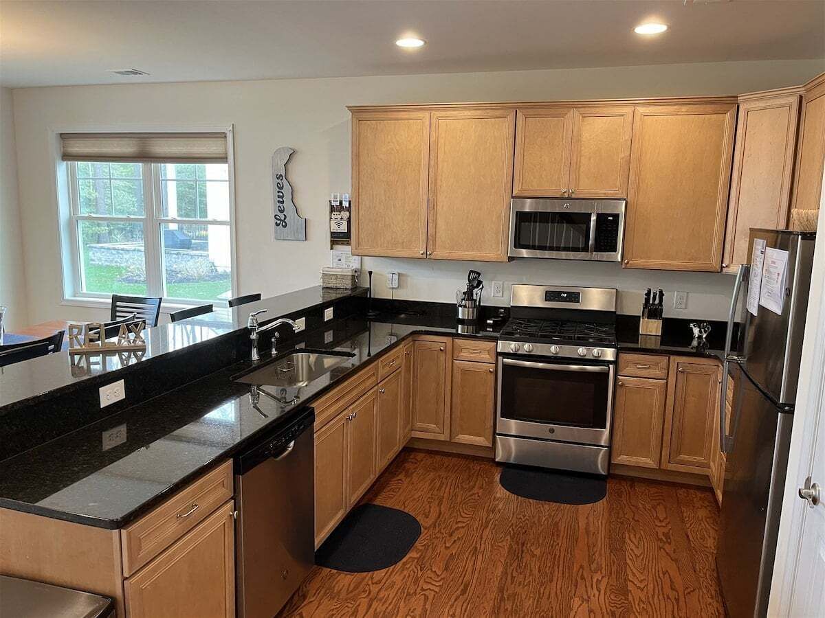 A modern kitchen with wooden cabinets, stainless steel appliances, and a black countertop.