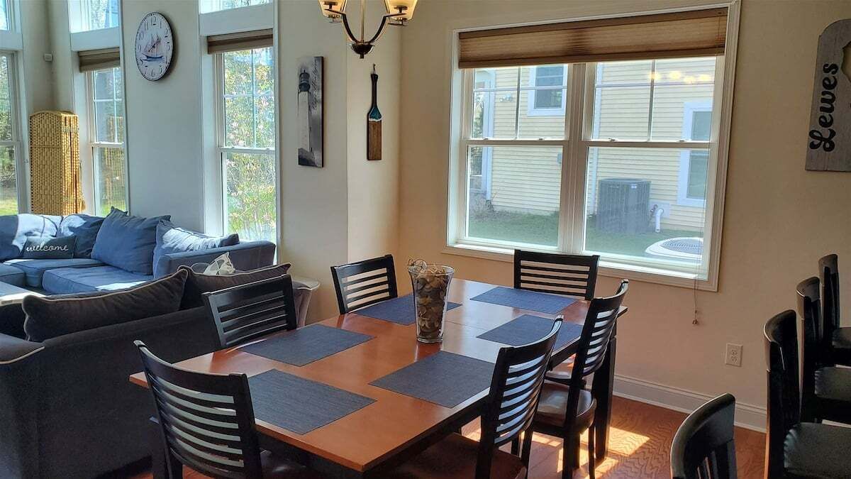 A dining area with a wooden table, black chairs, and a vase of flowers.