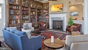A living room with a fireplace, bookshelves, a blue sofa, a coffee table, and a television.
