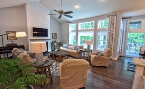 A living room with a fireplace, a ceiling fan, and large windows. - NEW Coastal Club Luxury *16117 Rock *4BR Ranch House - Sleeps 10 (Lewes)