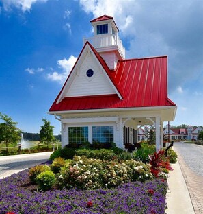 A white building with a red roof and a tower, surrounded by colorful flower beds. - NEW Coastal Club Luxury *16117 Rock *4BR Ranch House - Sleeps 10 (Lewes)