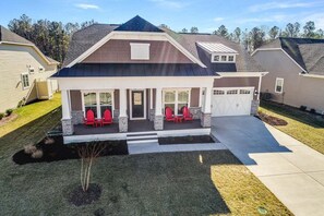 A two-story house with a covered porch, a garage, and a well-maintained lawn. - Coastal Club * 4BR Luxury House (Lewes)