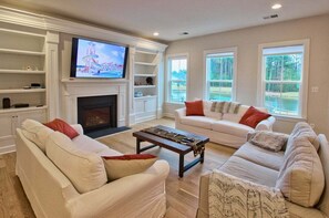 Ein Wohnzimmer mit Kamin, Fernseher und einer Couch.