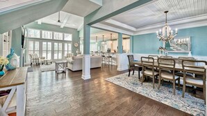 A spacious living area with a dining table, chairs, and a chandelier.
